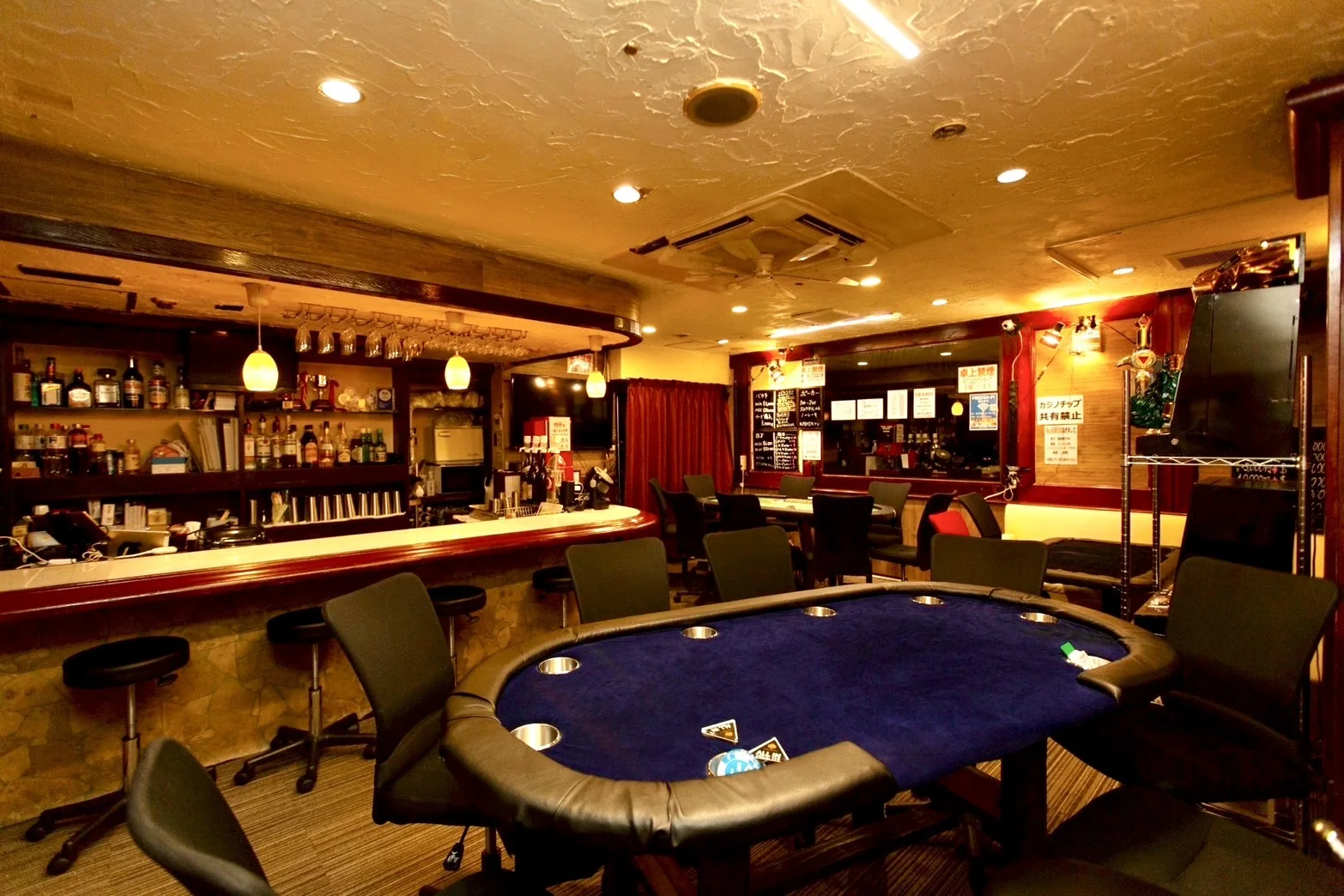 青いポーカーテーブルとバーカウンターの店内